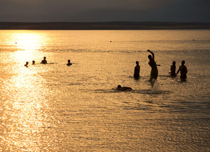 Silhouette Of Young People Playing In The Sea In Sunset photo