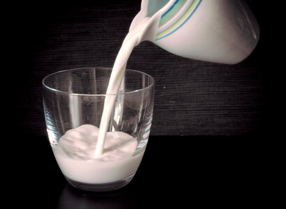 Milk is poured into a glass photo