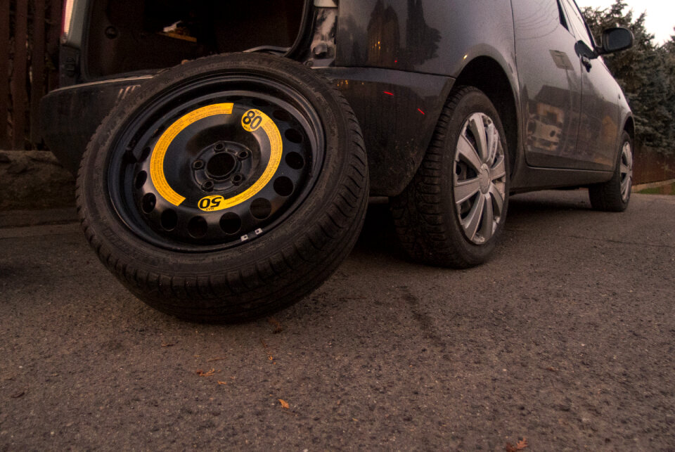 The spare tire leaning against a black car