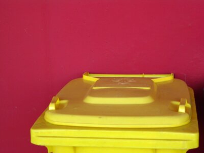 Yellow trash bin against red wall photo
