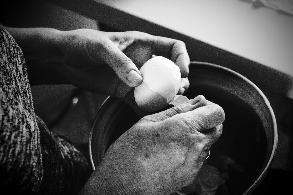 Old woman peeling an egg
