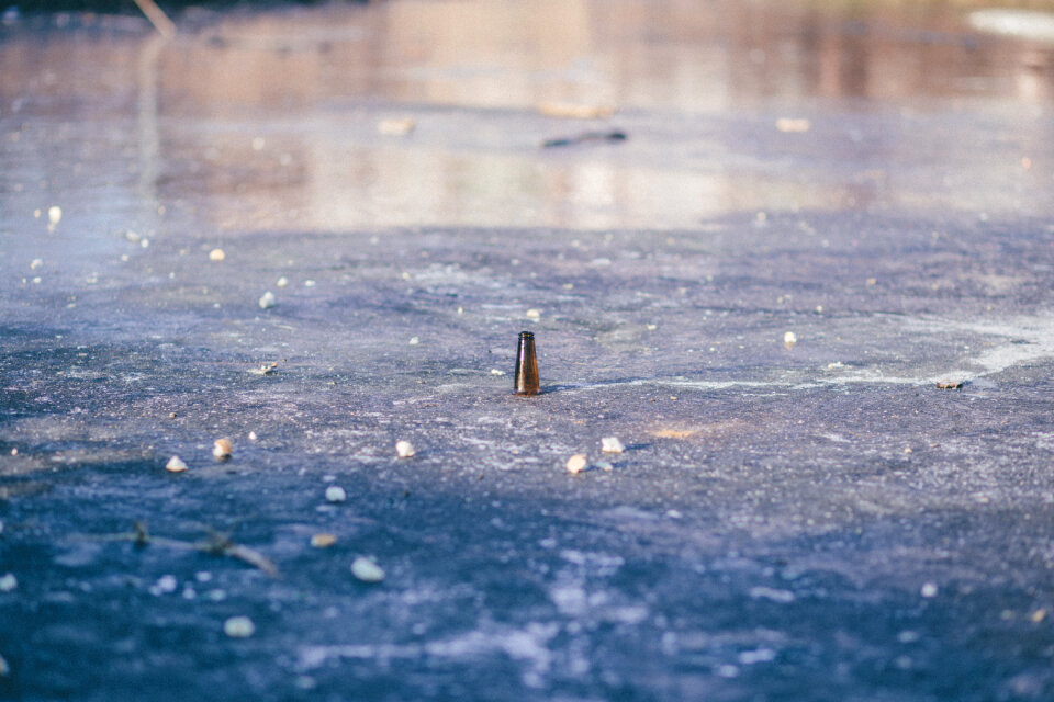 Beer bottle in a frozen pond