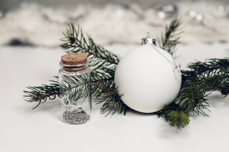 White and silver bauble with a spruce twig photo