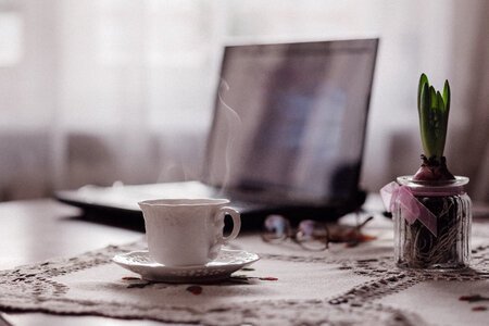 Cup of coffee, flower and laptop photo