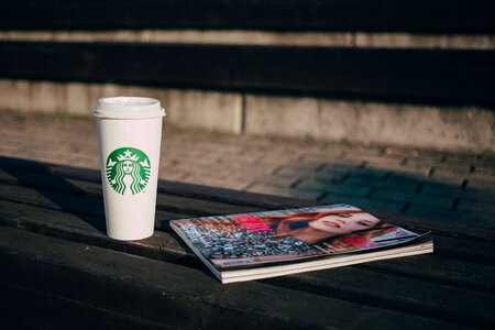 Coffee and a magazine on a bench photo