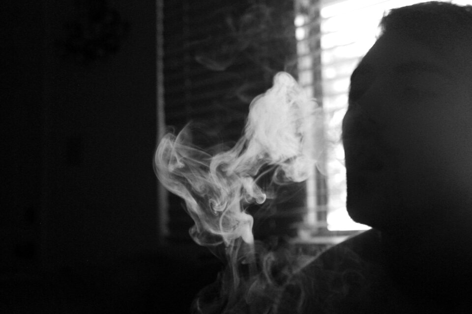 Gray Scale Photo of Human Smoking Inside the Room