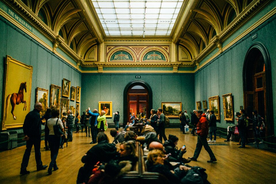 People Walking on Wooden Floor Inside Green Walled Building