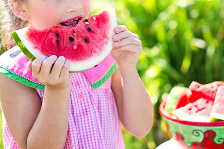Girl Eating Sliced Watermelon Fruit Beside Table photo