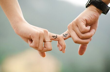 Man and Woman Interlocking Index Fingers With Anchor Tattoos photo