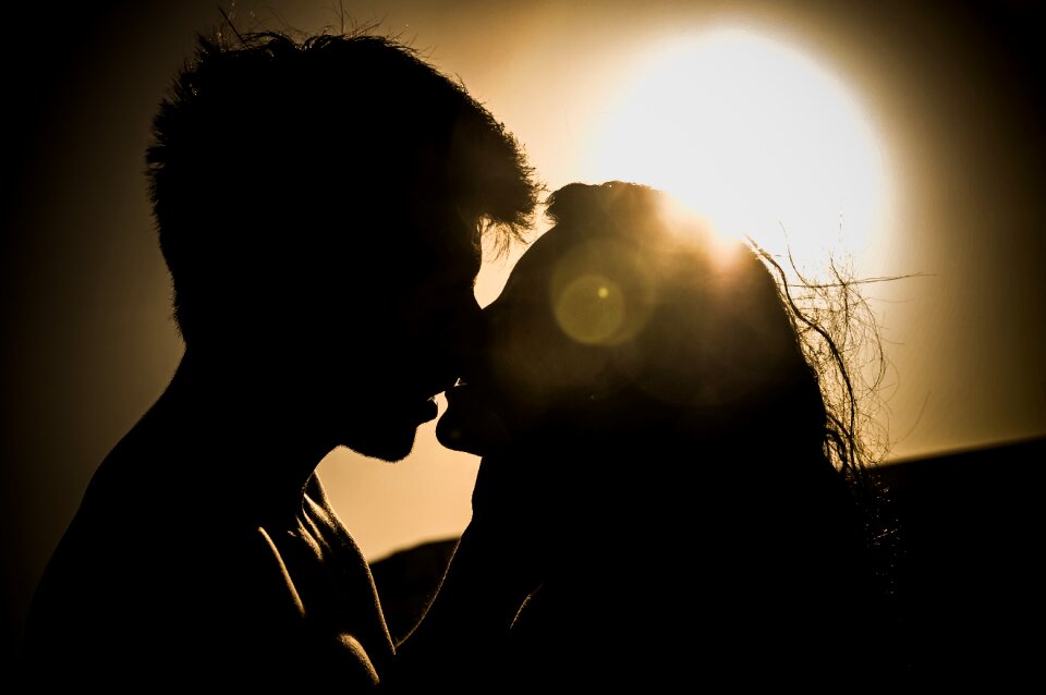 Silhouettes of Couple Kissing Against Sunset photo