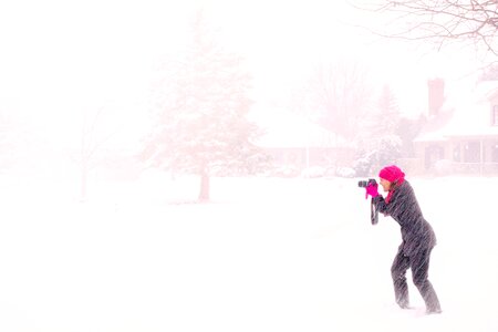 Woman in Pink Hijab Holding Black Dslr Camera Under Raging Snow during Daytime photo