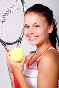 Girl in White and Orange Stripe Tank Top Holding Black Tennis Racket photo