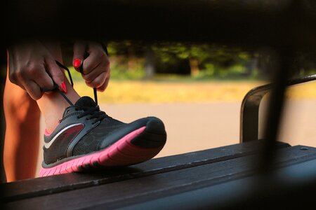 Woman in Black and Pink Sneaker Tying Lace of Her Shoe photo