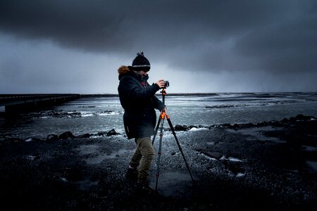 Man in Blue Coat Holding a Tripod With Camera photo