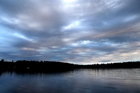 Silhouette of Tress Beside Body of Water on Cloudy Day photo