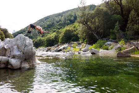 Man in Black Shorts Back Flipping Into River during Daytime photo