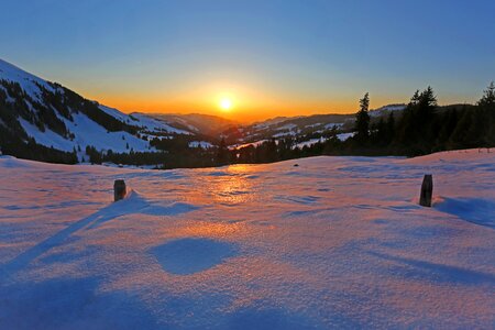 Sun Rising in Horizon over Snow Coated Mountains photo