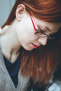 Woman Looking Down Wearing Red Eyeglasses photo