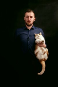 Man in Grey Dress Shirt Holding White and Orange Fur Cat photo