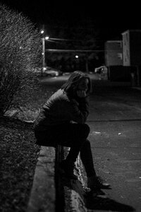 Woman Wearing Jacket Sitting on Concrete during Night Time photo