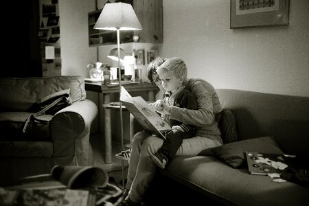 Grayscale Photography of Child on Lap of Woman While Reading Book photo