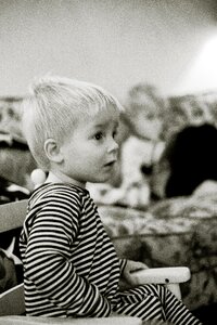 Grayscale Photo of Boy Sitting on Armchair