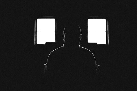 Person Sitting in Dark Room With 2 Window photo