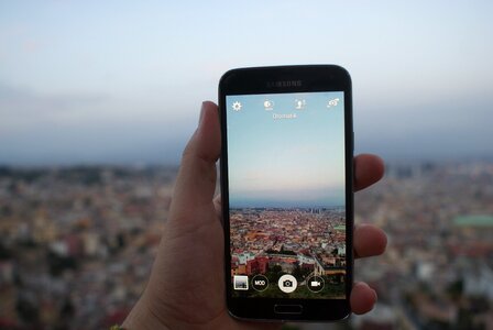 Person Holding a Black Samsung Galaxy Android Smartphone Taking a Picture of Cityscape over Blue and White Sky during Daytime photo