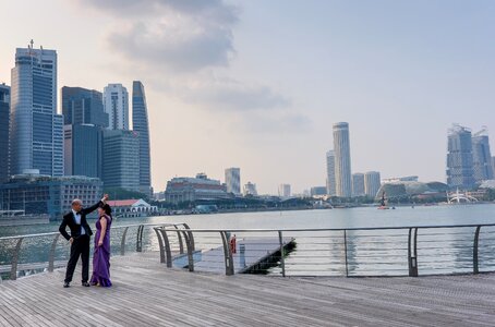 Man and Woman Dancing Beside Body of Water Under White Sky photo