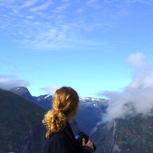 Woman Wearing Black Long Sleeve Shirt Watching on Green and Brown Mountain Under White and Blue Sky during Daytime