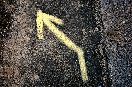 Yellow Left Arrow Sign on Black and Grey Surface photo