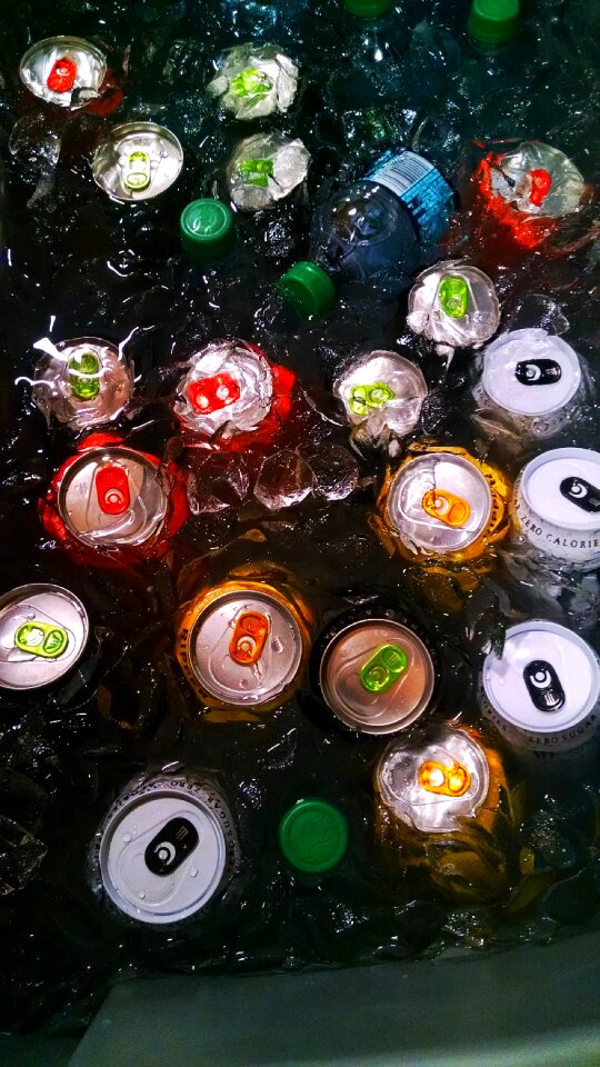 Drinking Cans and Bottle on Water With Ice Cubes