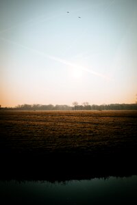 Body of Water Beside Brown Grass during Sun Set photo