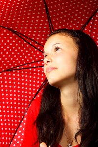 Black Haired Woman in Red Sweater Wearing Silver Dog Pendant Necklace Holding Black Red White Polka Dotted Umbrella photo