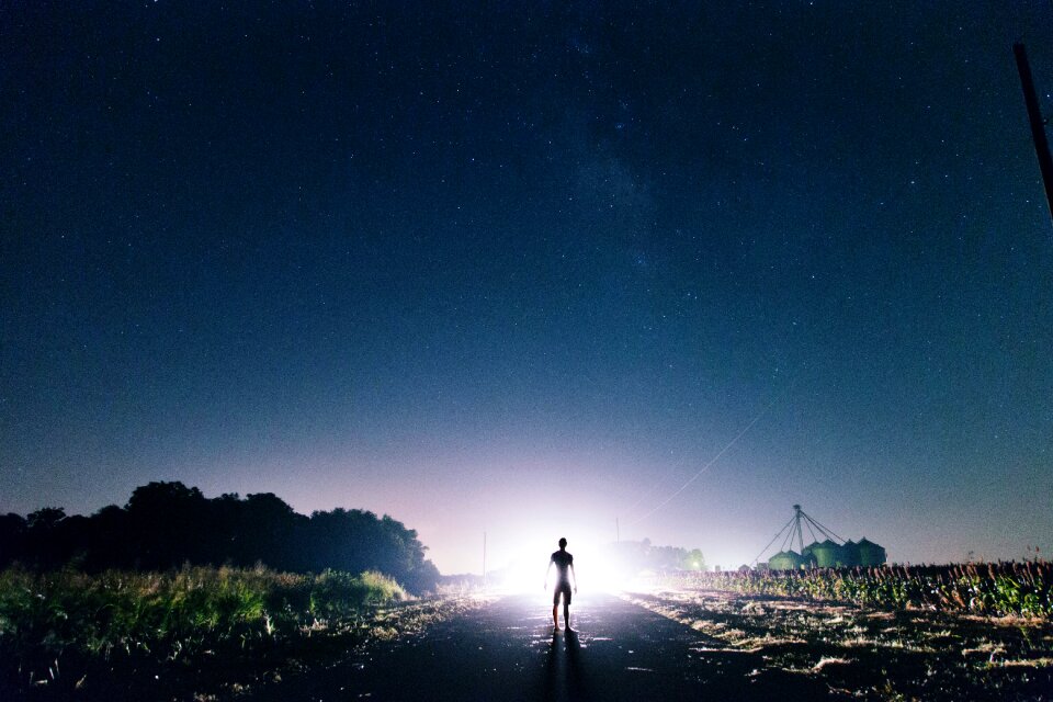 Man Standing on the Road Near Green Grass during Sunrise photo