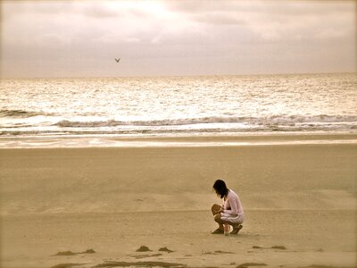 Woman in Pink Cardigan Sitting on Seashore photo