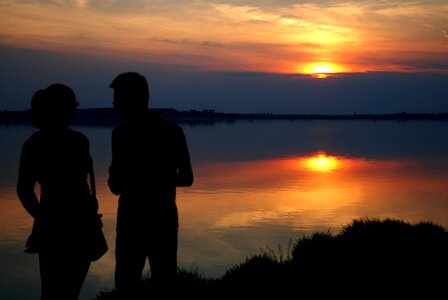 Silhouette of Man and Woman Near Water during Sun Set photo