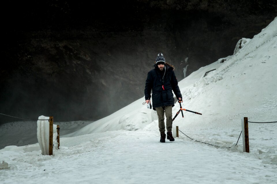 Man Wearing Black Jacket Brown Jeans and Black Shoes Walking on Snow