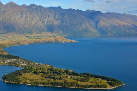 Green Field Island in the Middle of Body of Water Near Mountains during Daytime photo