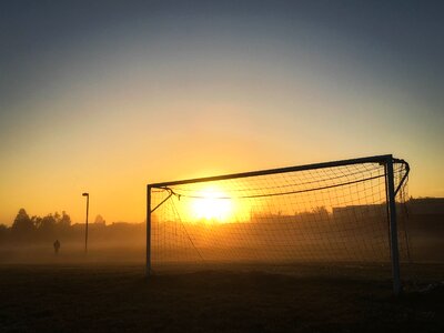 Person Jogging Near Soccer Goal during Sunrise photo