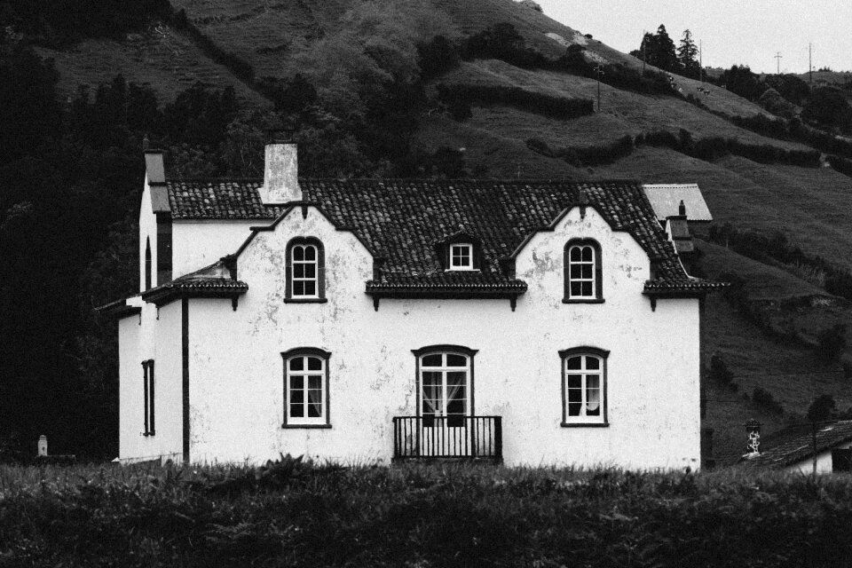 Grey Scale Photo of House in Green Fields