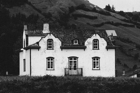 Grey Scale Photo of House in Green Fields