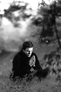 Grayscale Photography of Man Sitting on Grass Field photo
