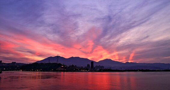 Silhouette Photo of City Buildings Near Sea With Mountain during Golden Time photo