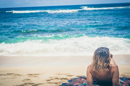 Woman Sun Bathing on Brown Sand Beach photo
