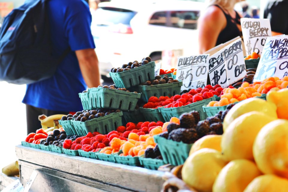 Man Wearing Blue Top And Black Bottom Standing Near Fruit Stand