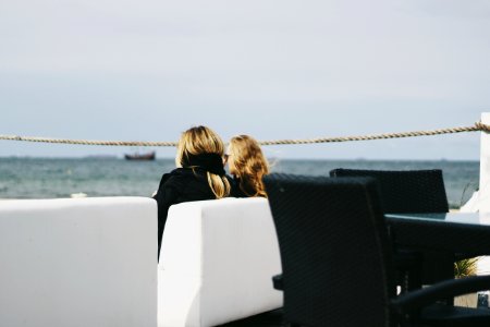 Two Women Sitting Near Body Of Water photo