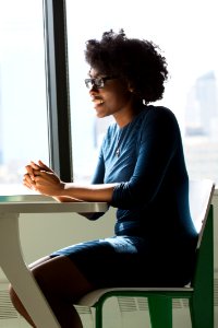 Woman Wearing Eyeglasses Sitting Beside Table And Window photo