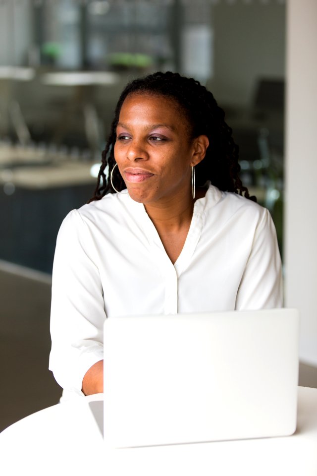 Woman Wearing White Button-up Shirt Sitting In Front Of Table