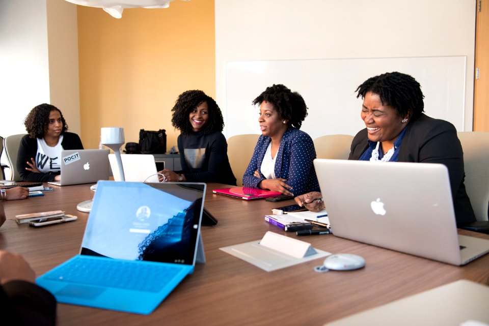 Group Of People Talking To Each Other In Front Of Brown Wooden Table